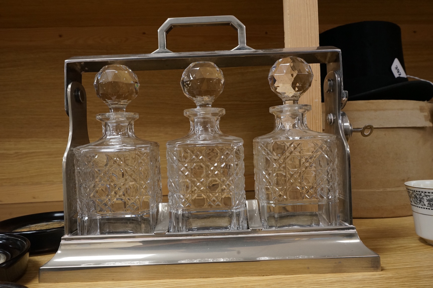 A silver plated three bottle tantalus, 34cm wide.